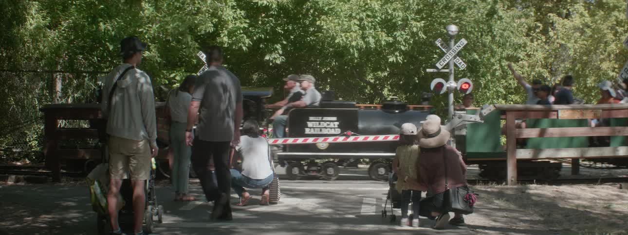 Children and parents wait at a railroad crossing for the train ride to stop