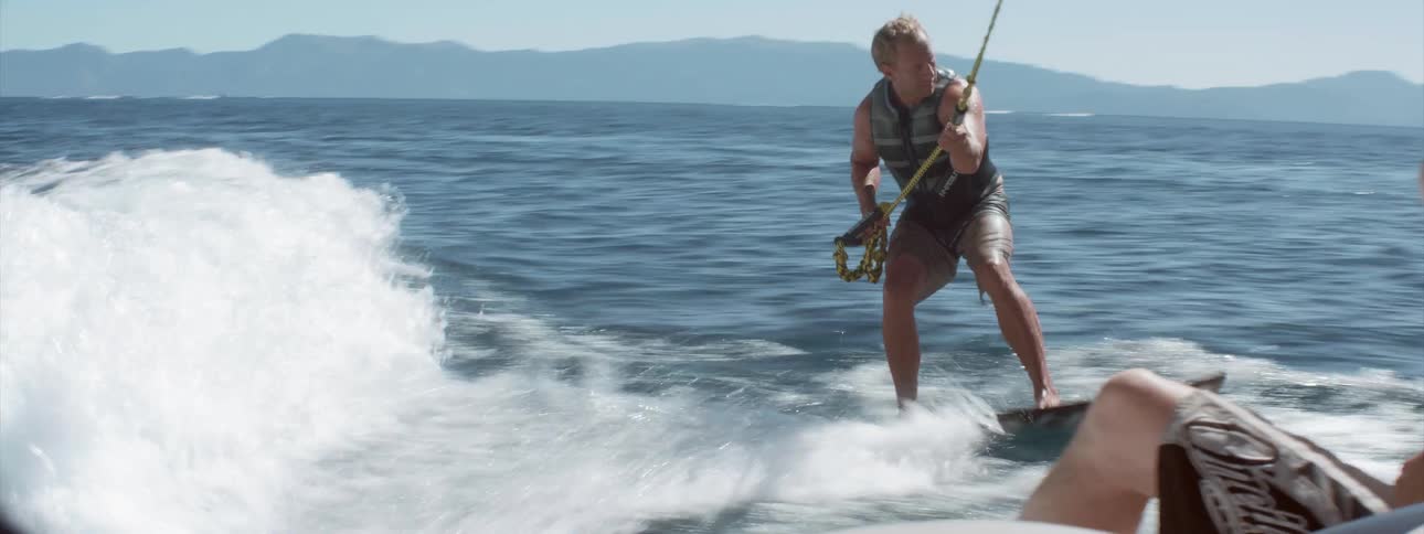 A man wakeboards on a lake on a sunny summer day