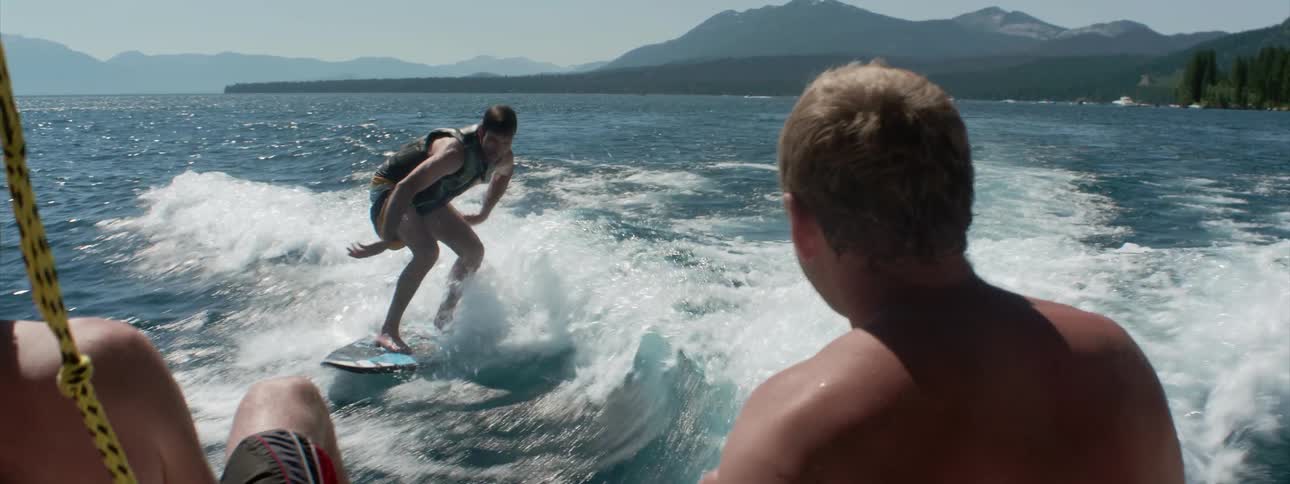 A young man surfs behind a boat