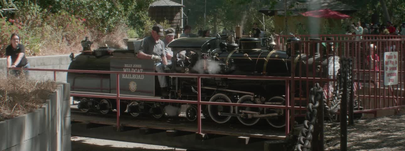 Two people sit on a tourist attraction train while an employee spins it