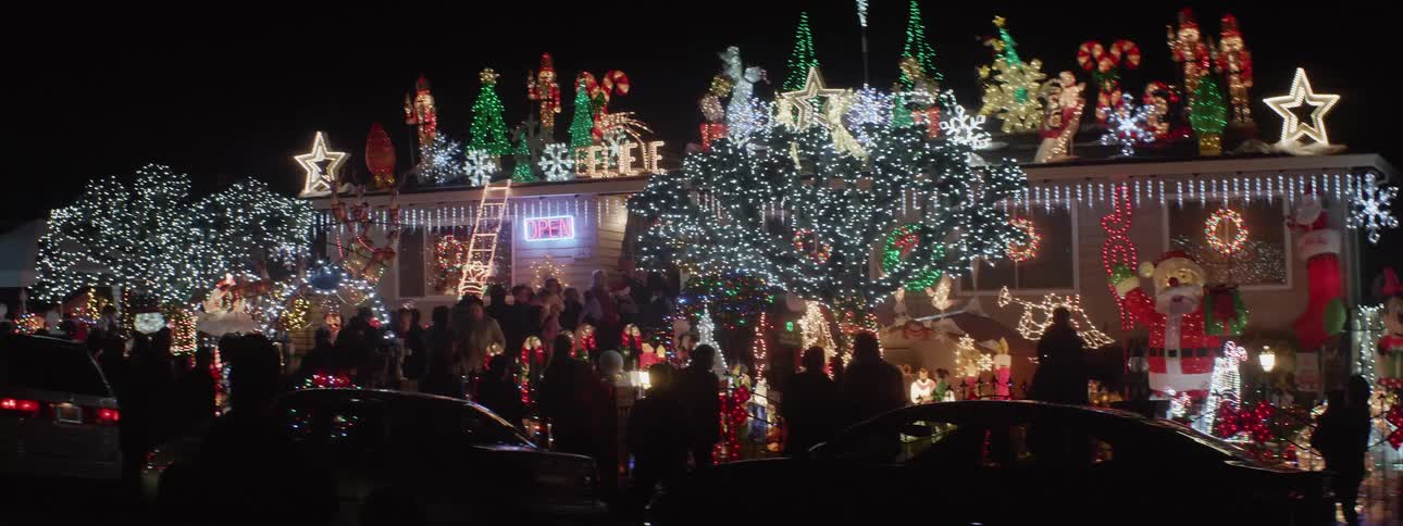 A group of people crowding around and lining up outside of a building covered in christmas decorations