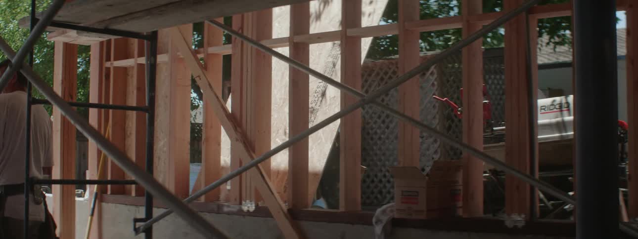 A man moving a large piece of wood to a house frame