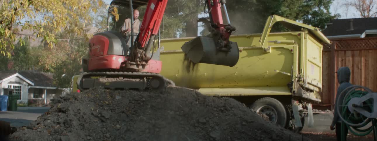 Excavator loading dirt into truck at worksite