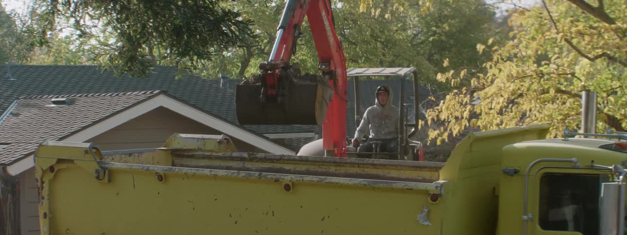 A construction worker operates an excavator in a residential area
