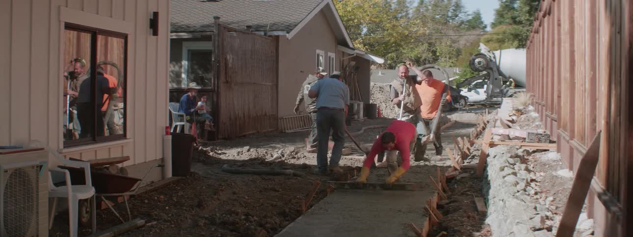 A crew of men lay a cement sidewalk