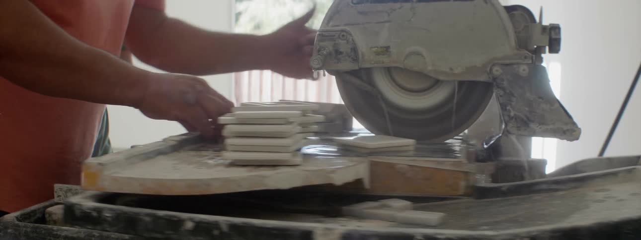 A man is cutting tile on a sliding tile saw