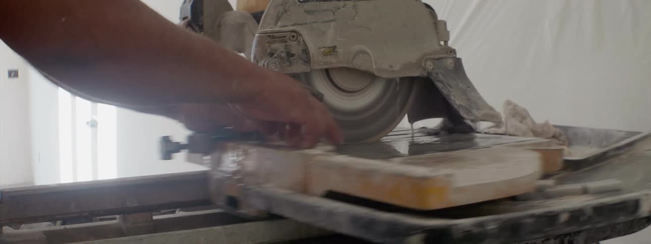 Professional worker cutting tile with circular electric saw