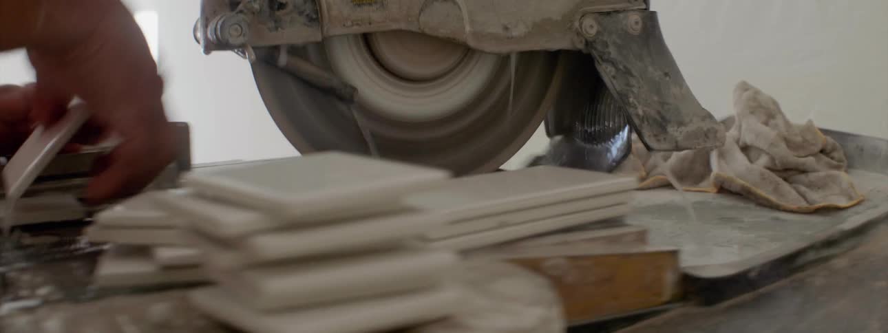 A person is cutting tiles on a machine