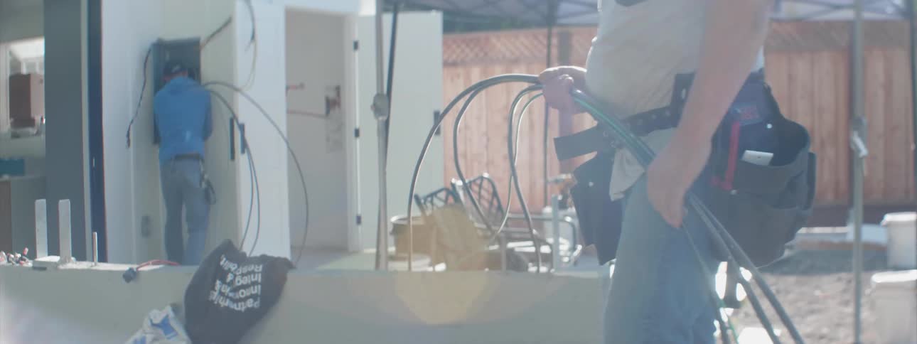 Two contractors feed wire to an electrical box