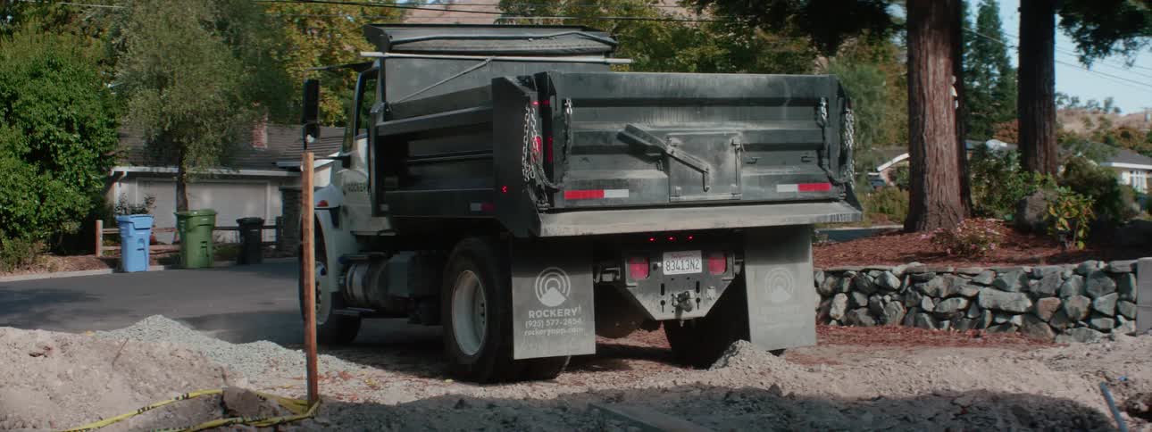 A man gets in the dump truck and begins pouring out the contents