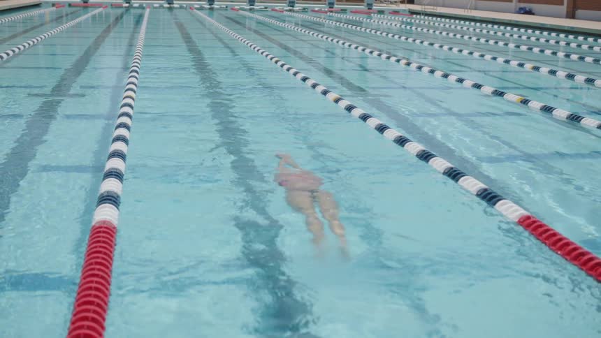 A woman swims under water in a swimming pool lane