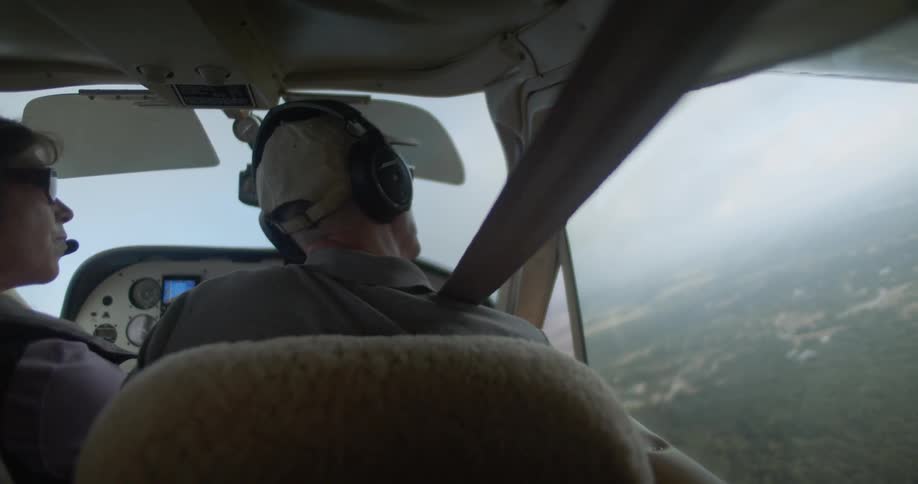A man pilots a small aircraft with a woman in the cockpit