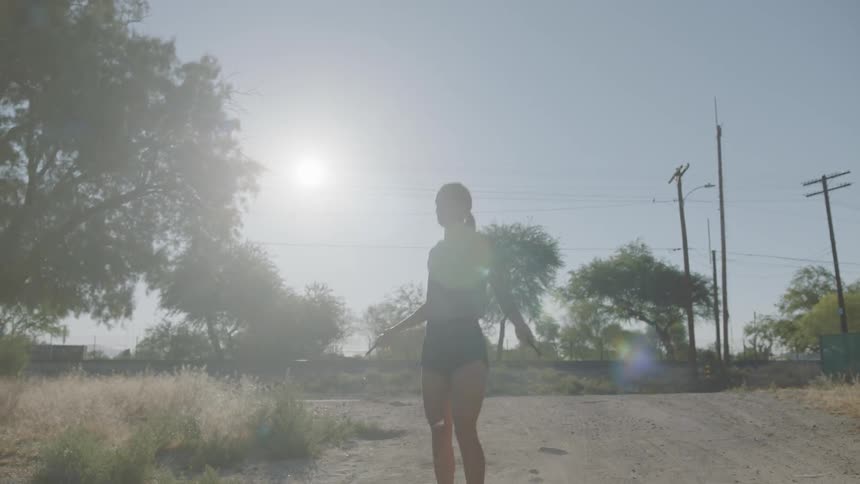 A woman jumps rope on a dirt road