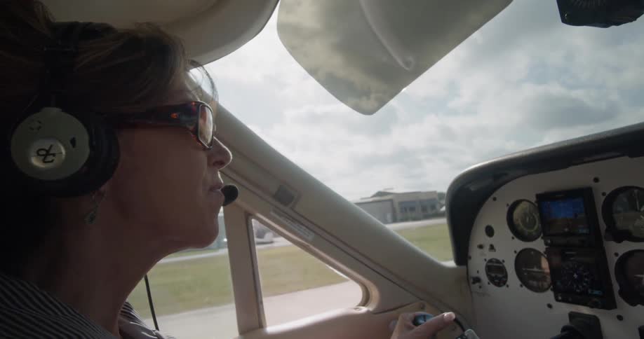 A female pilot taxis on the runway in a small plane