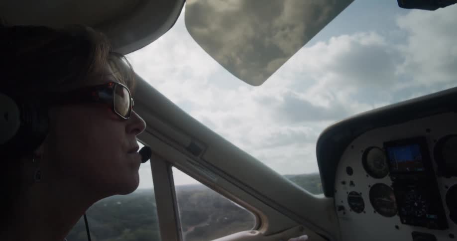 A woman piloting an aircraft over a forest