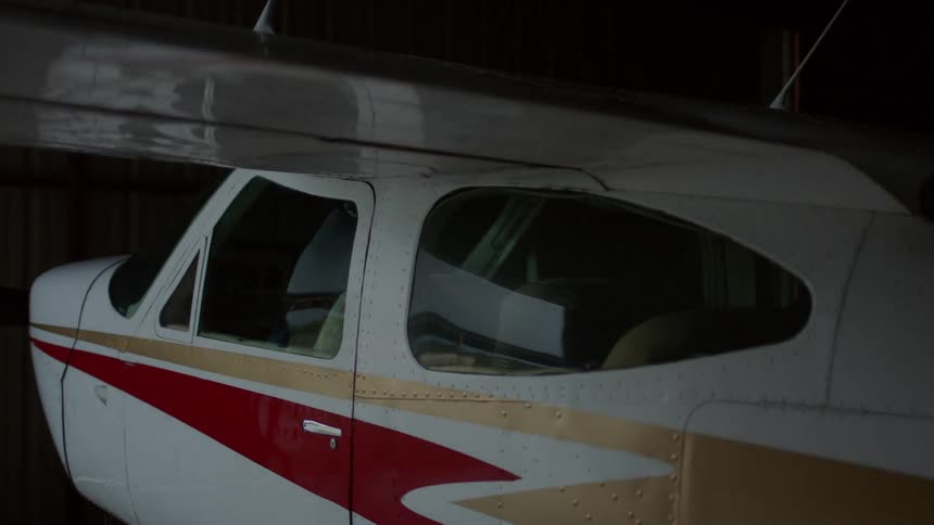 A person opening the hanger for a small airplane