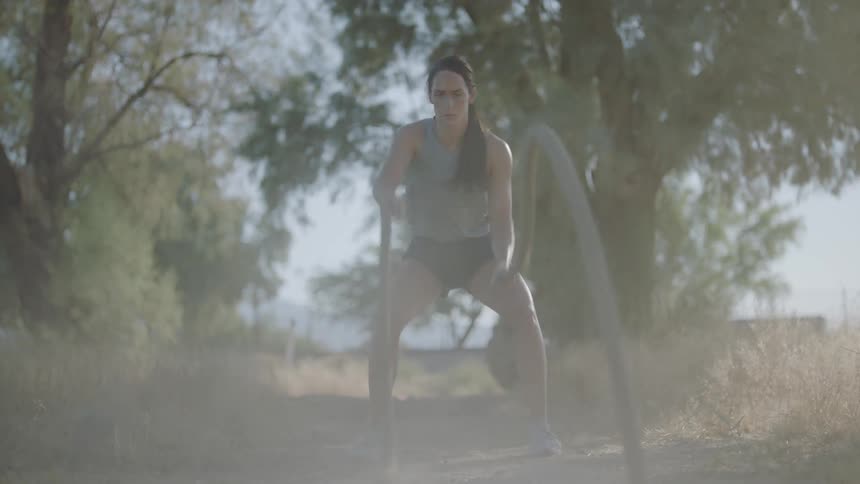 Woman exercises with battle ropes in the forest