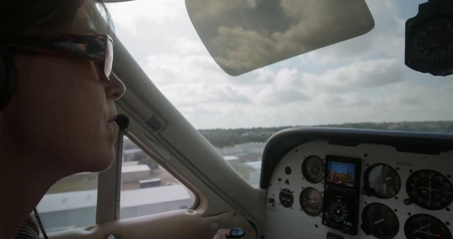 A female pilot flies a small plane low coming in for a landing
