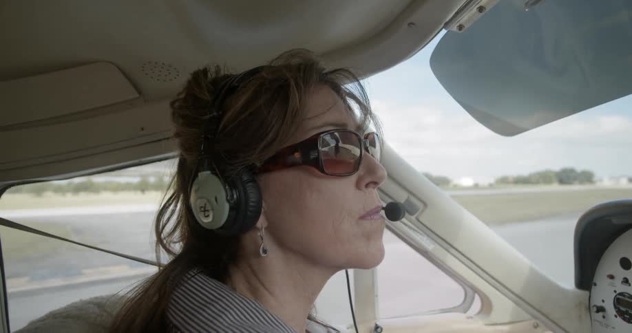 Female pilot wearing sunglasses operates the airplane on the runway in airport