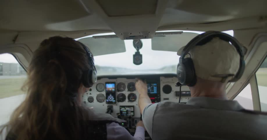 A man and woman sit in the cockpit of an aircraft