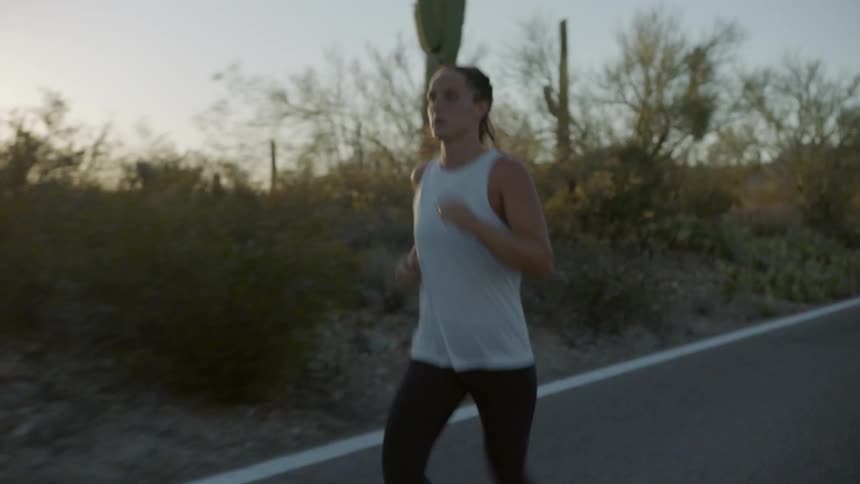 A woman jogging down a road in the desert
