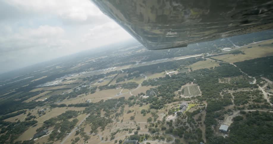 An airplane wing with fields and the sky in the background
