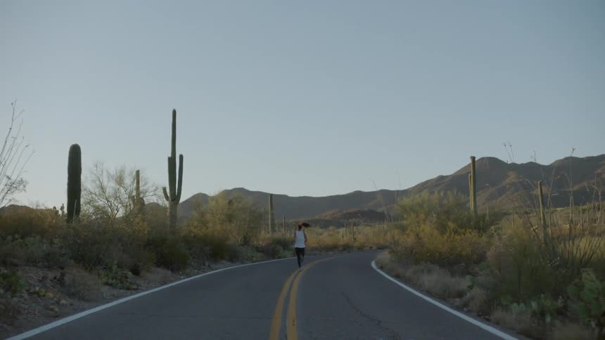 A woman jogs down the middle of a paved road out in the desert
