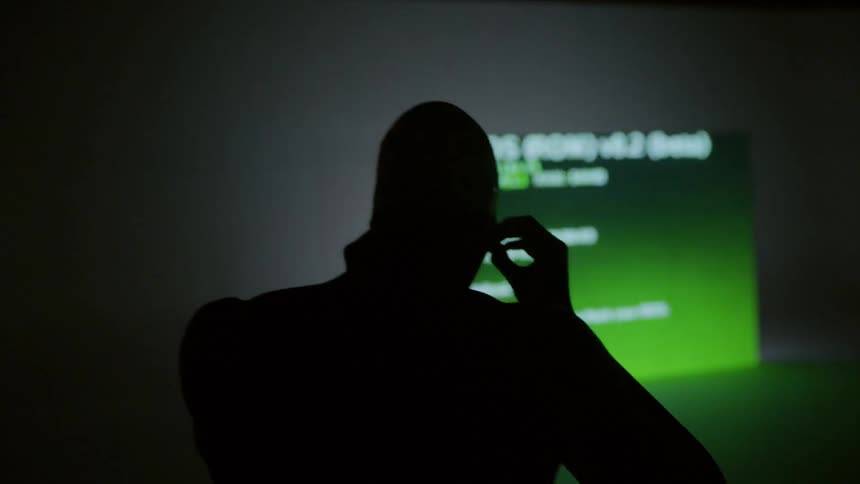 A man wearing goggles walks over to a large flashing digital video screen