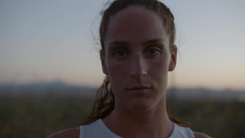 Runner woman looks at the camera at dusk