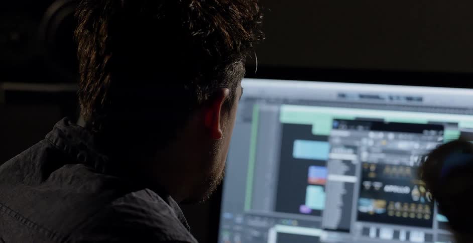 A man subtly nods his head to the beat of music as he looks at a computer display