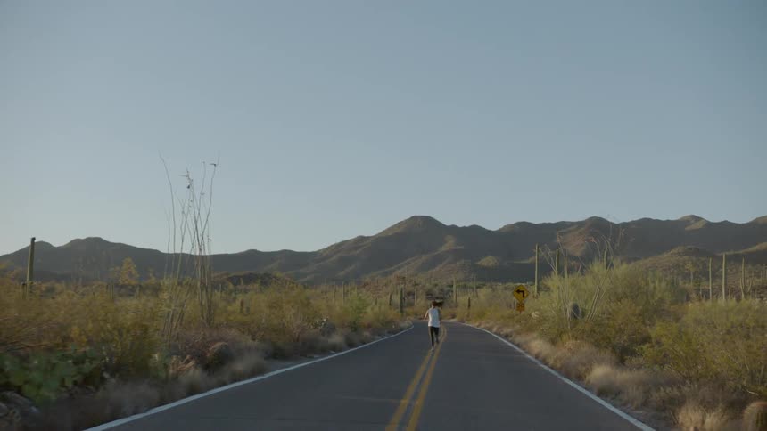 A woman jogs down the center line of a two lane road in a rural area