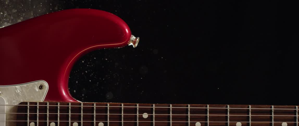 A red guitar on its side in dark studio