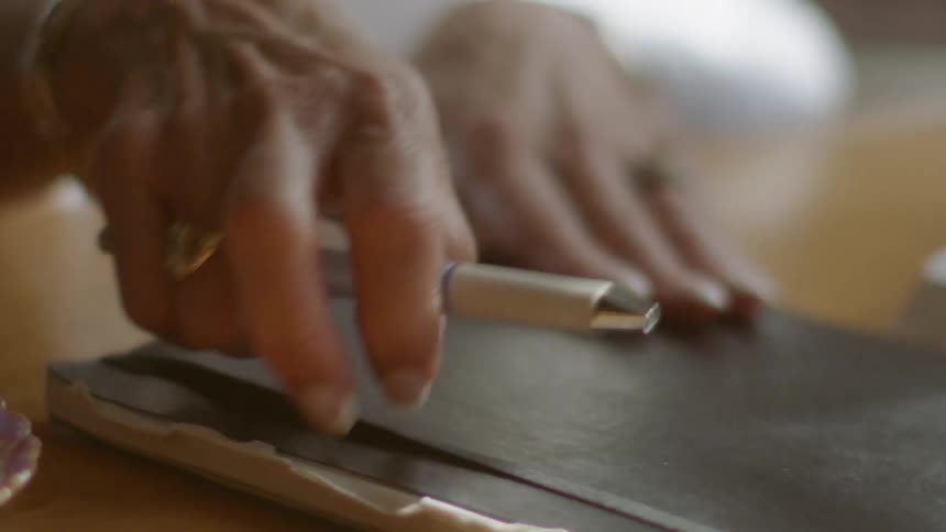 A person lifts their notebook and pen from the table