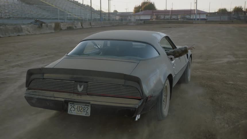 A car drives in a dirt filled arena