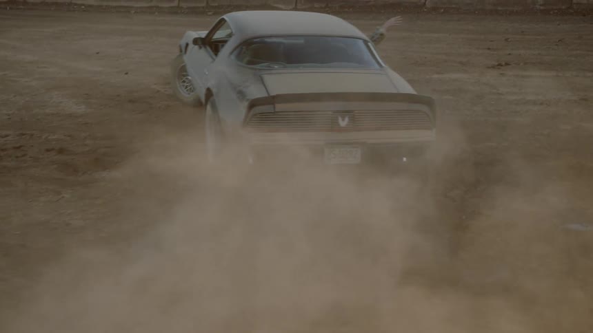 A car driving on dirt with a man and a woman inside