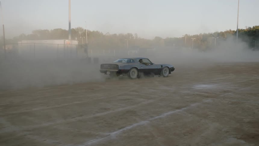 A classic car starts to spin as it races through a dirt field