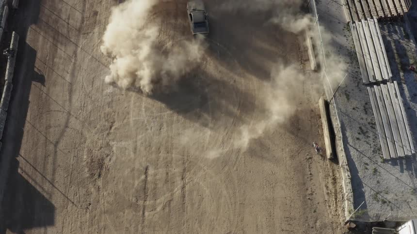 Aerial shot of car doing stunts on dirt construction yard