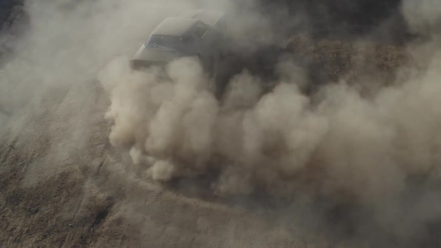 A car turns around making dust as its wheels spin
