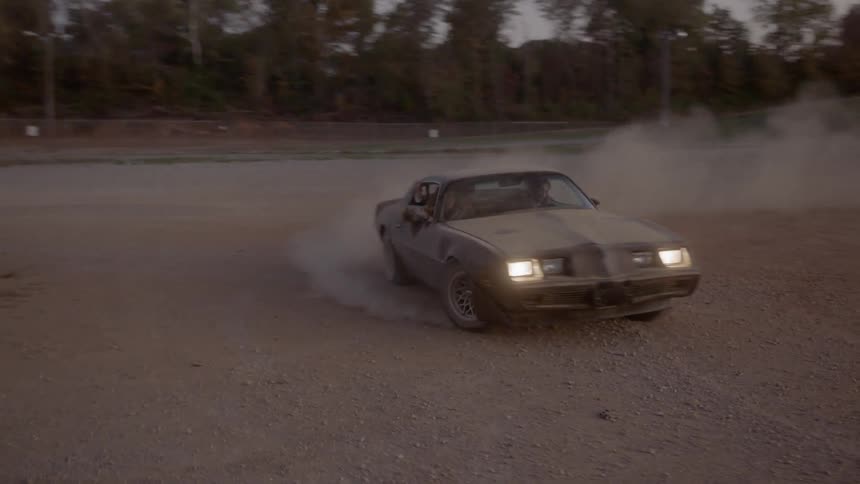 An old sports car does donuts on a dirt track