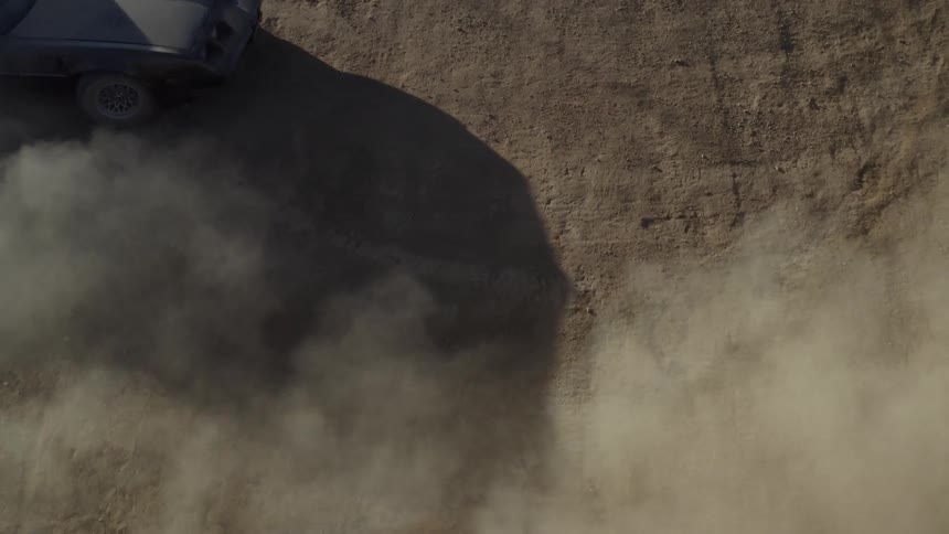 A black muscle car spins a cookie in a dirt field