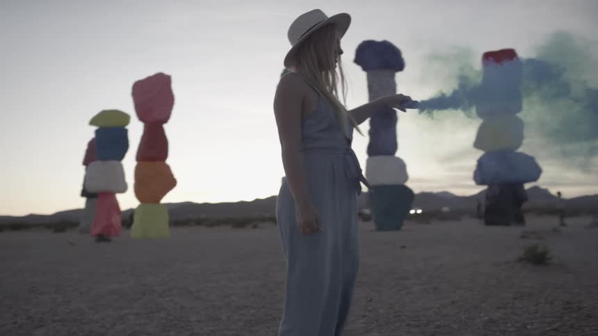 A blonde female holding up a blue flare at a festival