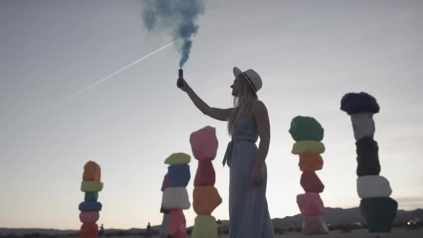 A woman is outdoors holding something that is smoking