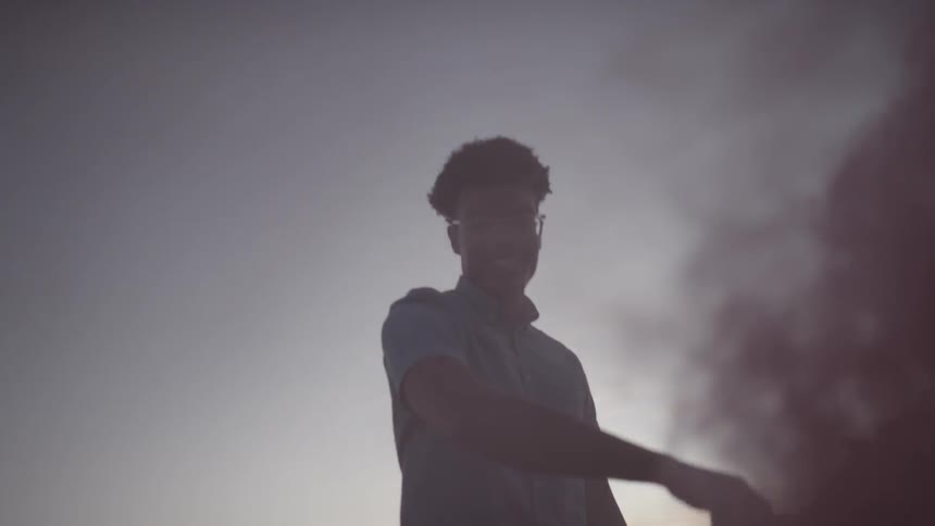 A man in the desert waving a red smoke flare