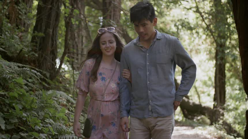 Young couple walking through forest on dirt path