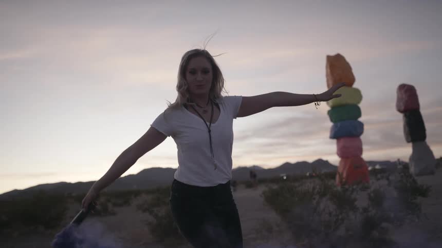 A young woman swings a tube in the air as colored powder releases from it
