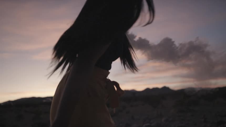 Asian woman smiling holds smoke torch and turns around at dusk