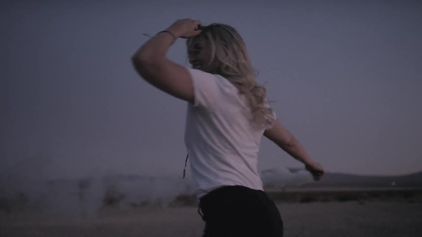 A young woman spins around and release powder in to the air
