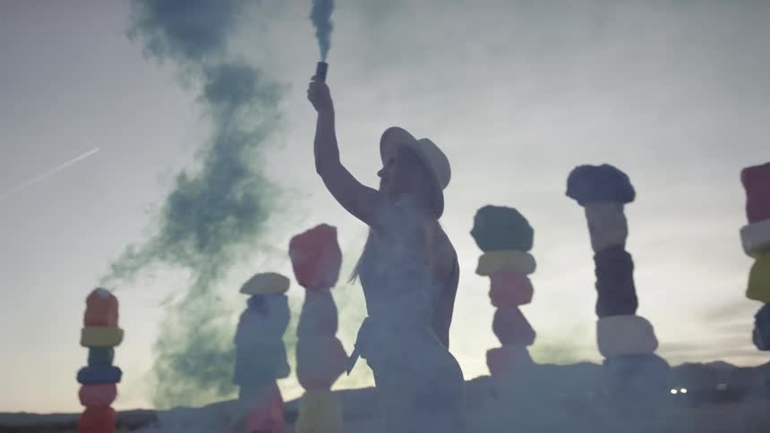 A young woman spins around and releases blue powder in to the air