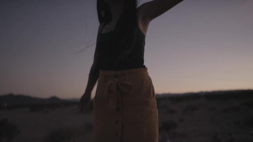 Woman dancing with smoke bomb on desert at sunset