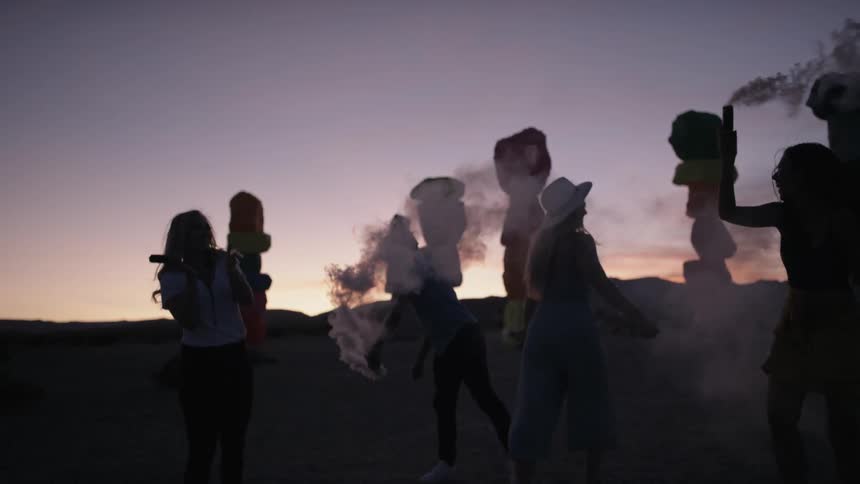 A group of women dancing around with smoke outdoors